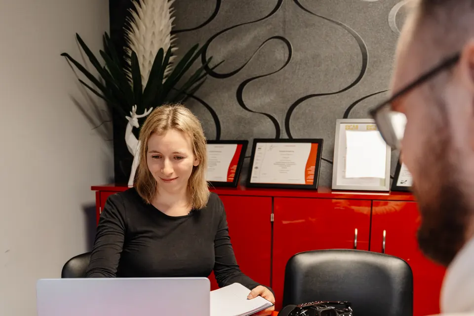 Anne bespricht am Laptop die Content-Planung mit einem Gesprächspartner